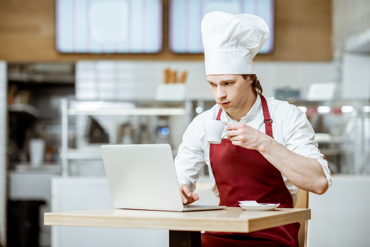Chef managing catering orders on a laptop