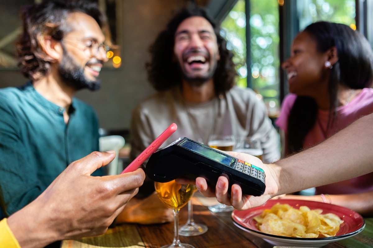 Friends paying with contactless NFC at a restaurant table