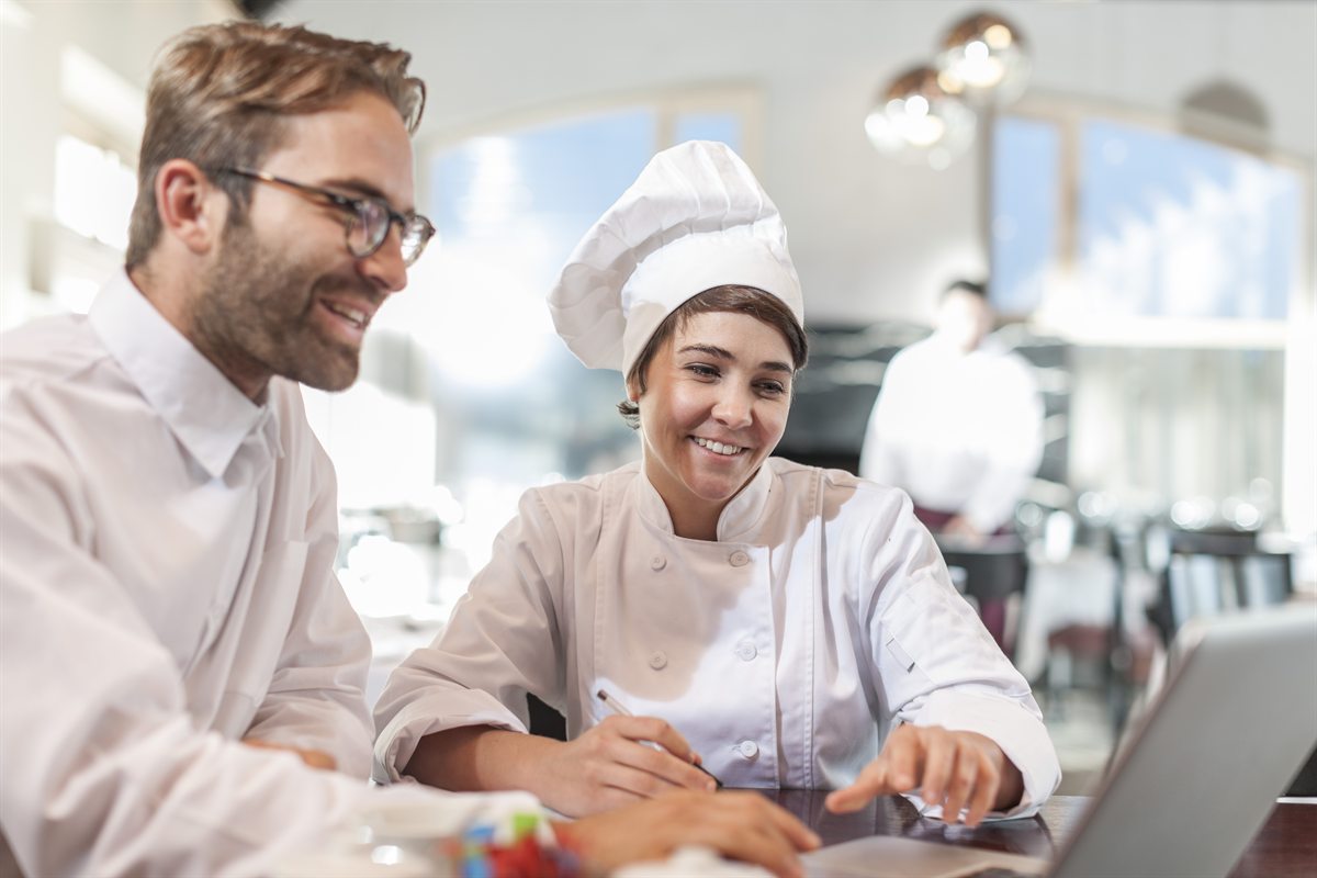 Restaurant chef and manager reviewing the menu on a laptop