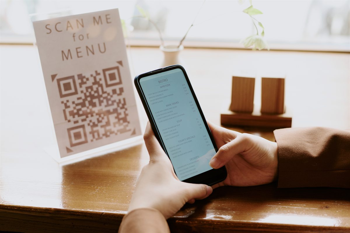 Guest viewing the menu on a phone beside a Scan-me QR stand